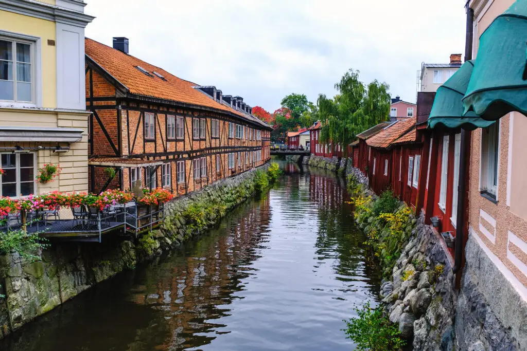 Scenic view of historic timber houses along a tranquil canal in Gamla Västerås, Sweden, perfect for cultural tourism and exploring Swedish heritage.