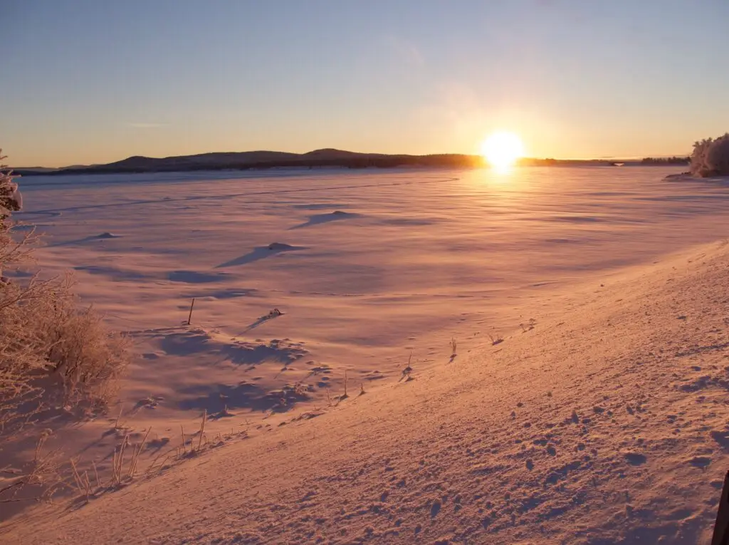 Winter sunset over the snow-covered landscape in Arjeplog, Sweden, showcasing the serene beauty of Scandinavian winters.
