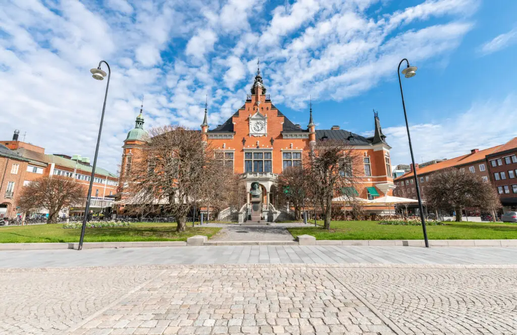 View of Umeå Town Hall in Sweden with Gustav II Adolf's bust, showcasing the ornate south facade on a sunny spring day with clear blue skies and leafless trees.