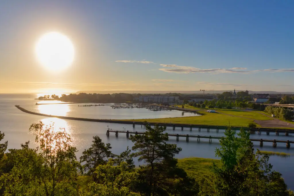 Sunrise over Vänersborg inlet in Sweden showcasing serene waters, piers, and distant cityscape, perfect for a scenic Scandinavian tour.