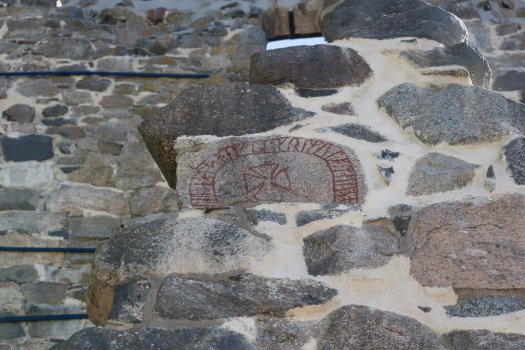 Historic carved stone with rune inscription at Saint Olof Church ruins in Sigtuna, Sweden, emphasizing ancient Scandinavian heritage.