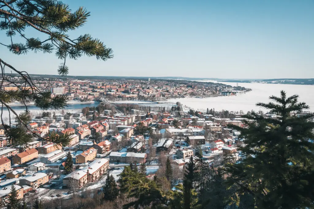 Aerial view of Östersund, Sweden, showcasing the picturesque cityscape with snow-covered roofs and the frozen Lake Storsjön during March, ideal for Scandinavian tours.