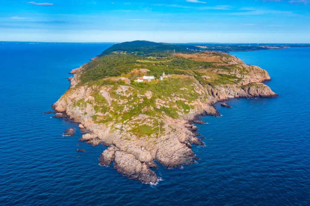 Aerial view of the rugged Kullaberg peninsula in Sweden, showcasing its cliffs and natural landscapes against the backdrop of the blue ocean.