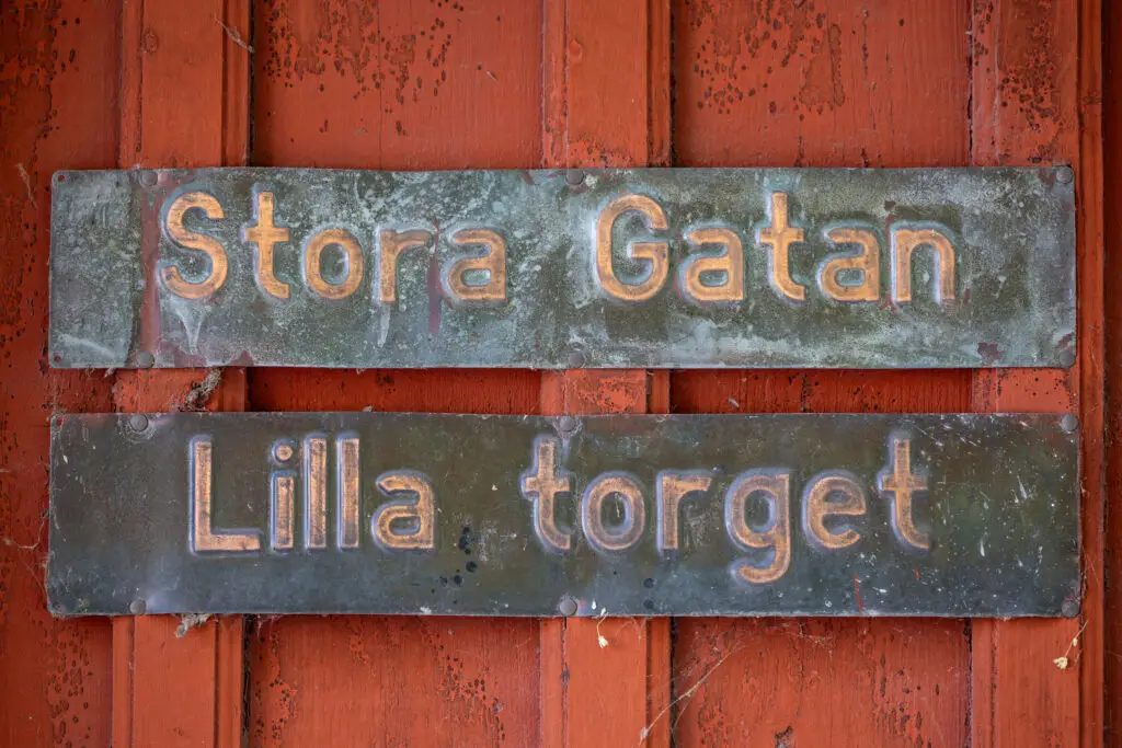 Vintage street signs for Stora Gatan and Lilla Torget on red wooden background in Sigtuna, Sweden.
