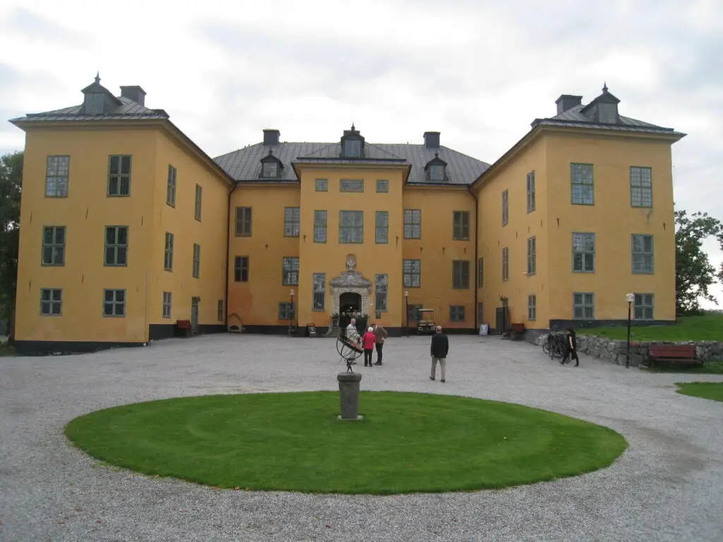 Visitors exploring the historical Venngarn Castle in Sweden, a prominent yellow building surrounded by a serene courtyard.
