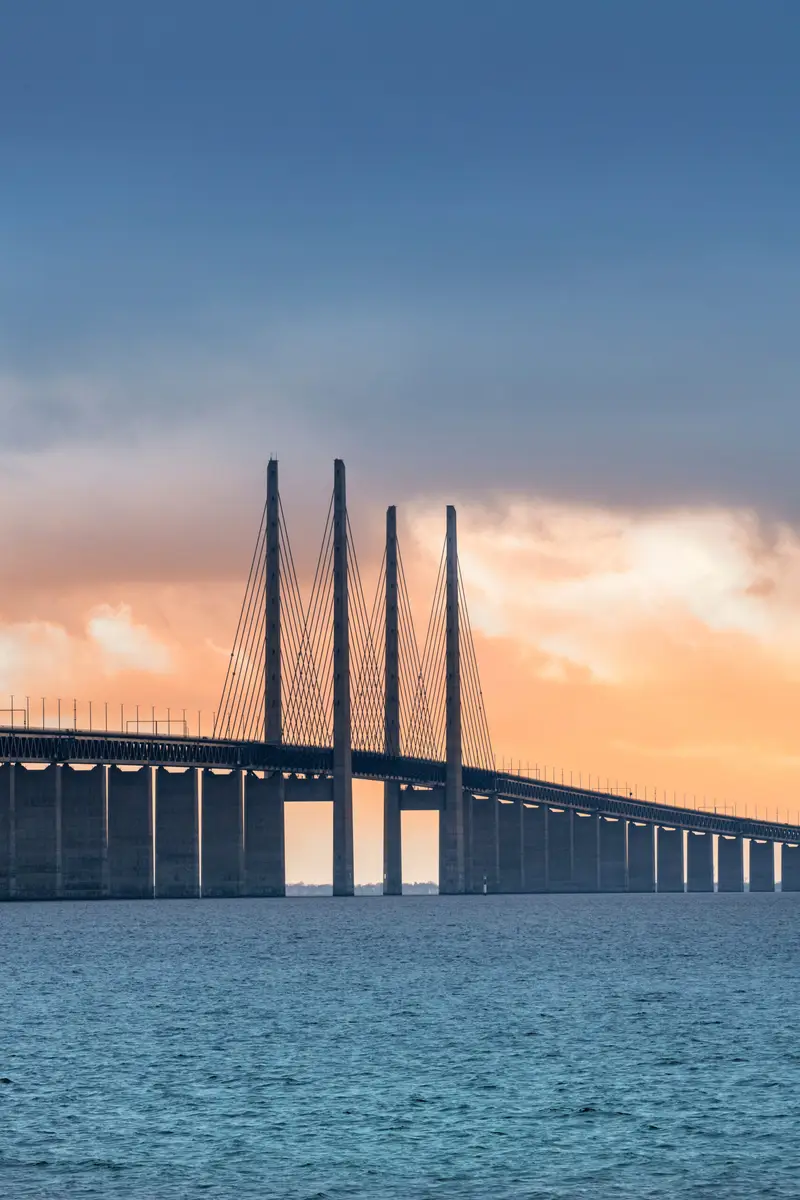 View of the Oresund Bridge at sunset, linking Sweden and Denmark over the ocean, highlighting modern architecture and connectivity.