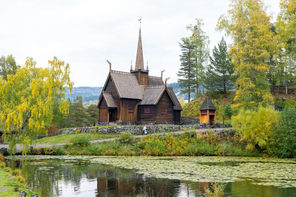 Garmo Stave Church surrounded by autumn foliage at Maihaugen Open-Air Museum in Lillehammer, Norway, reflecting cultural history and architecture.